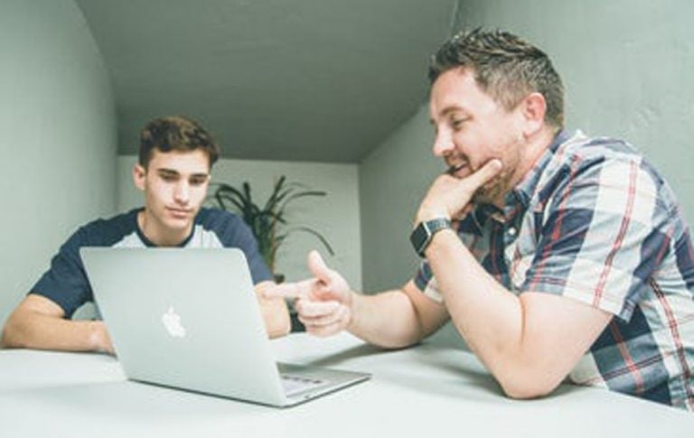 Man helping another on a computer