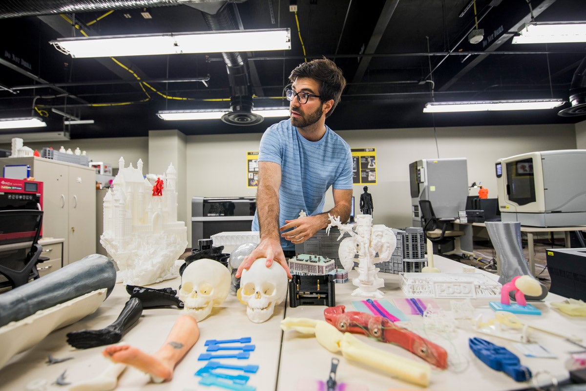 Fluvio Lobo, lead development engineer at the Prototype, Development and 3D Print Lab, showcases two skulls that were 3D printed at UCF to help surgeons at Nemours Children's Hospital plan the best way to remove a tumor from a patient. (Photo by Steven Diaz)