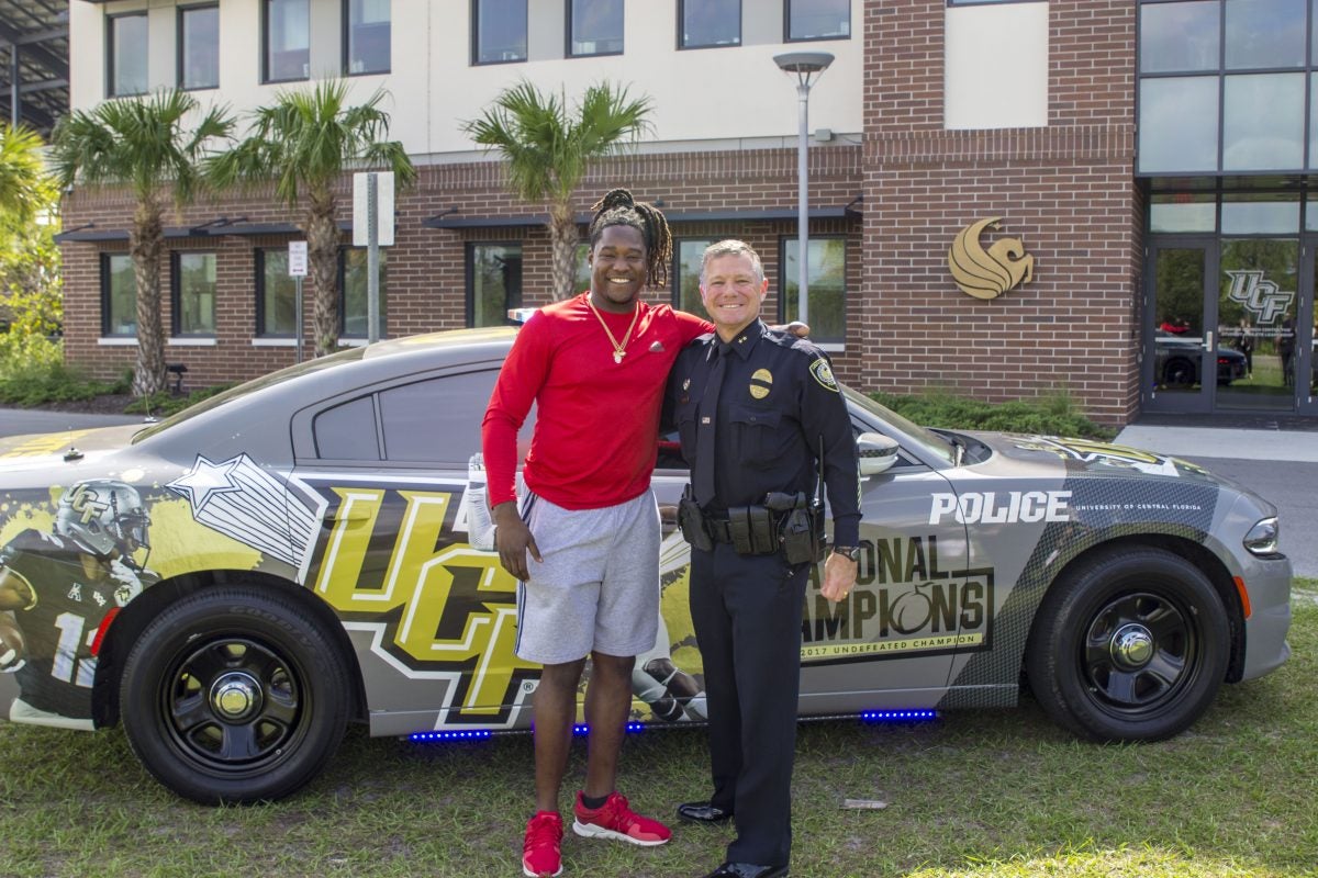 Carl Metzger greets Knights football player Shaquem Griffin, who stopped in April to see the police car commemorating the team's championship season. Metzger, chief deputy at the time, was named UCF's police chief in June, and Griffin now is a rookie linebacker in the Seattle Seahawks training camp. (Photo by Amanda Sellers '13)