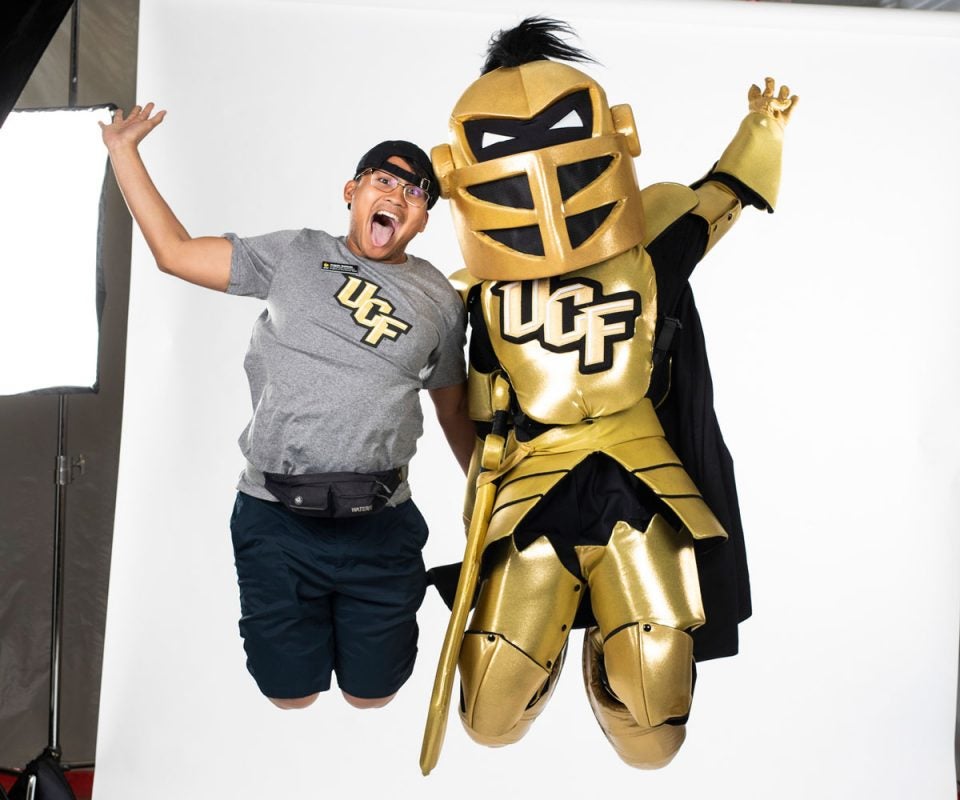Knightro hops into a photo with UCF senior Angelo Baldado.