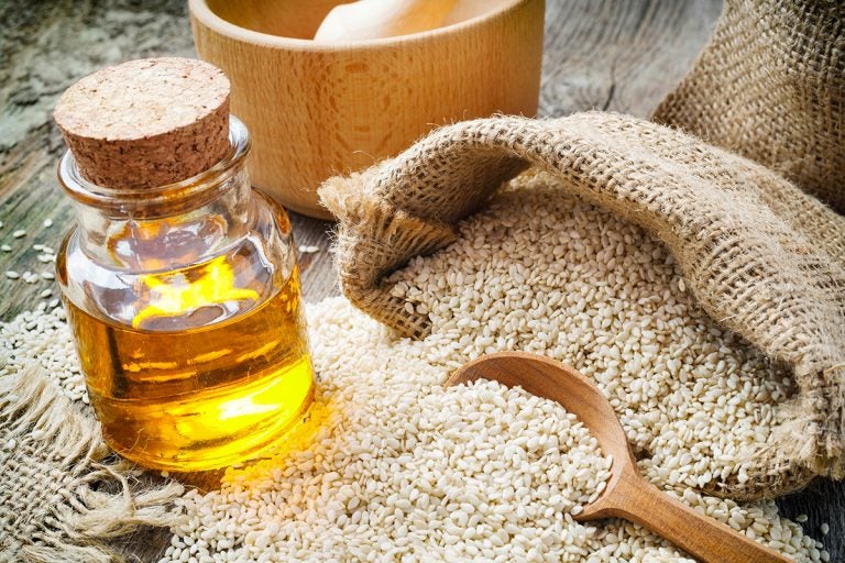 sesame seeds in sack and bottle of oil on wooden rustic table