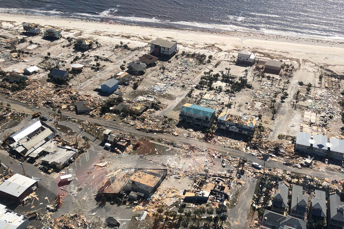 aerial view of homes ruined by hurricane damage with a beachline and ocean in view