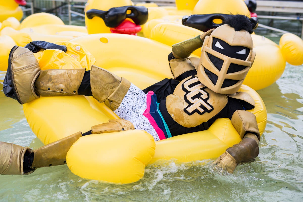 Knightro wears swim trunks and lays in an inflatable duck while floating on the water.