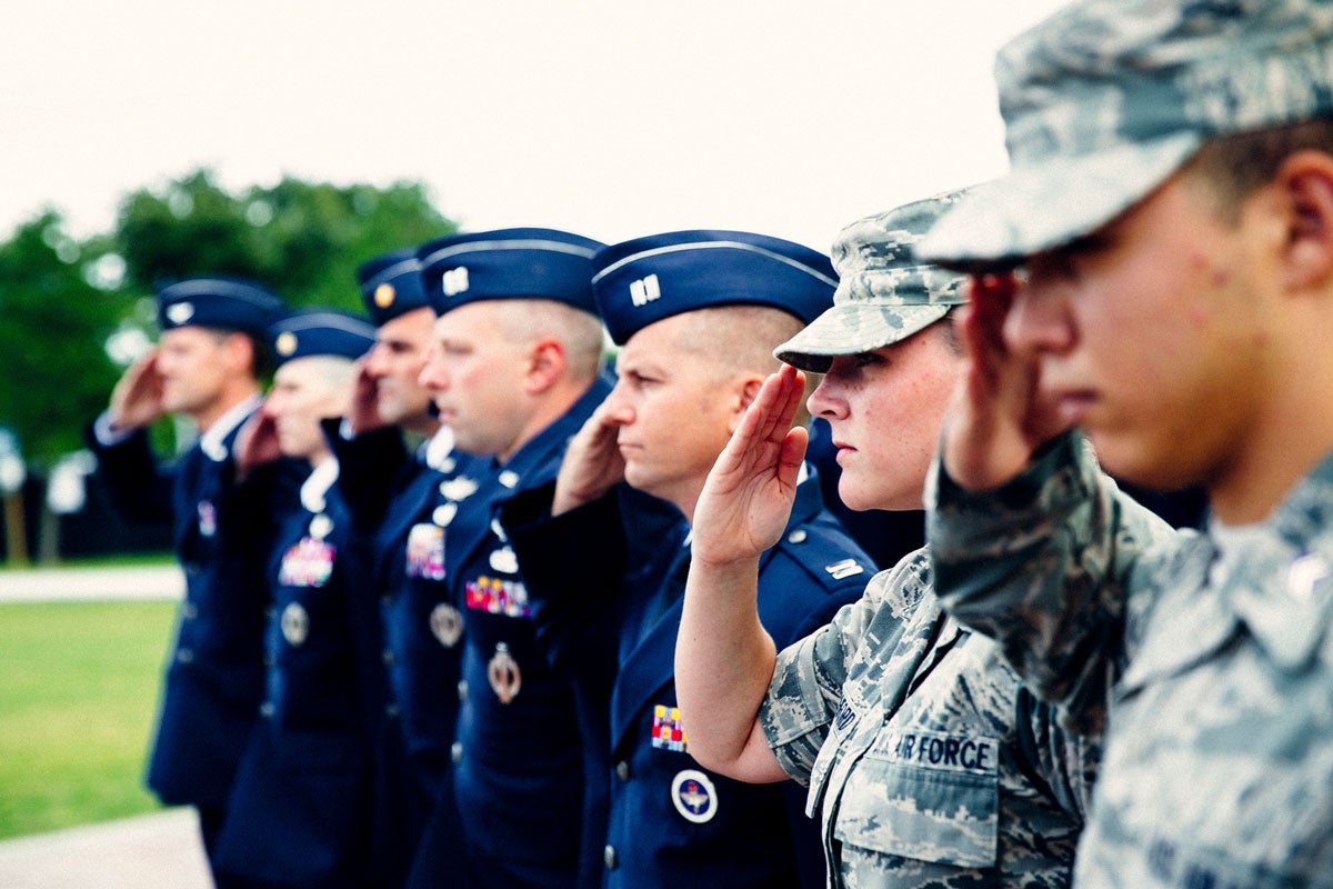 Seven men and women dressed in uniform stand at salute