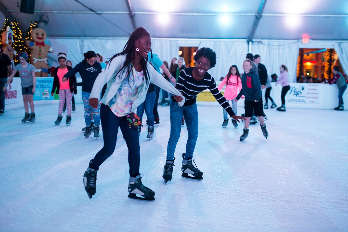 A group of people ice skate while holding hands