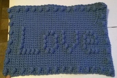 Section of the crocheted blanket that says "Love"