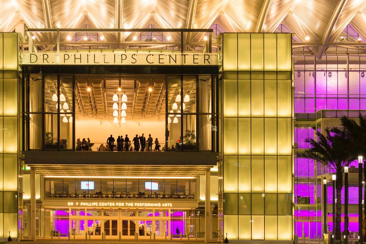 Square building lit up at night in gold color