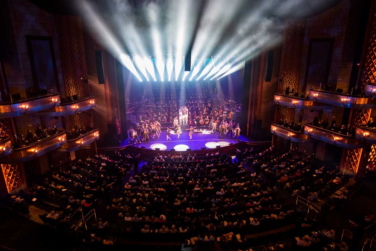 Large auditorium with stage lights shining on a purple-lit stage