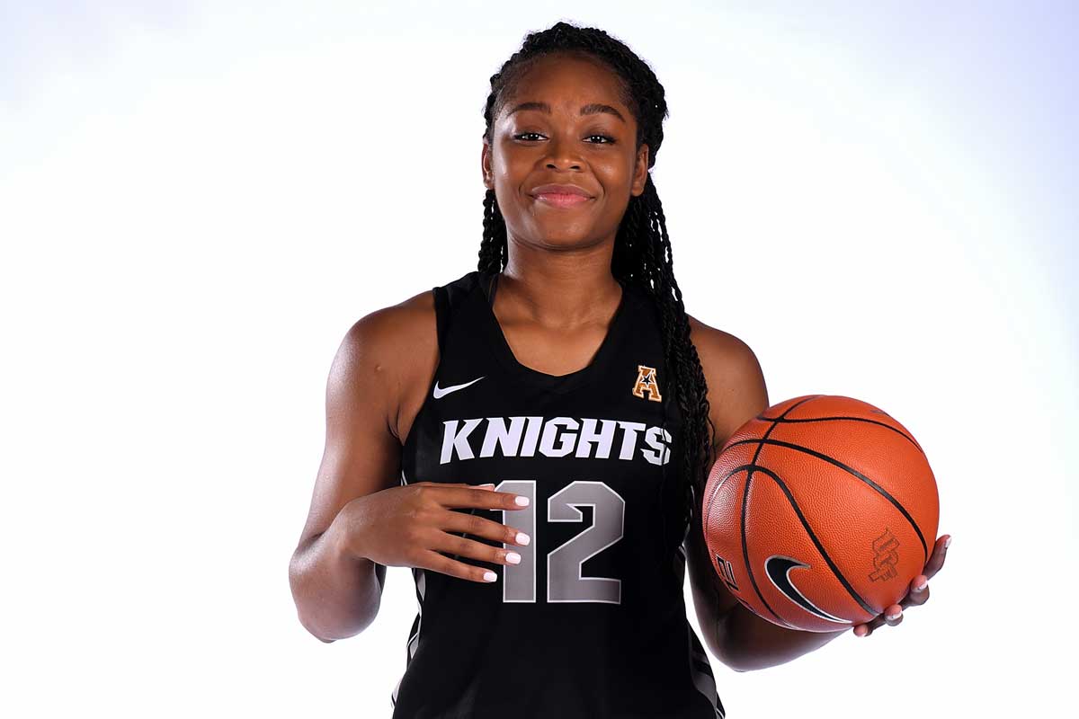 Nyala Shuler of the women's basketball team poses with a Nike basketball in her left hand in her #12 Knights black jersey.