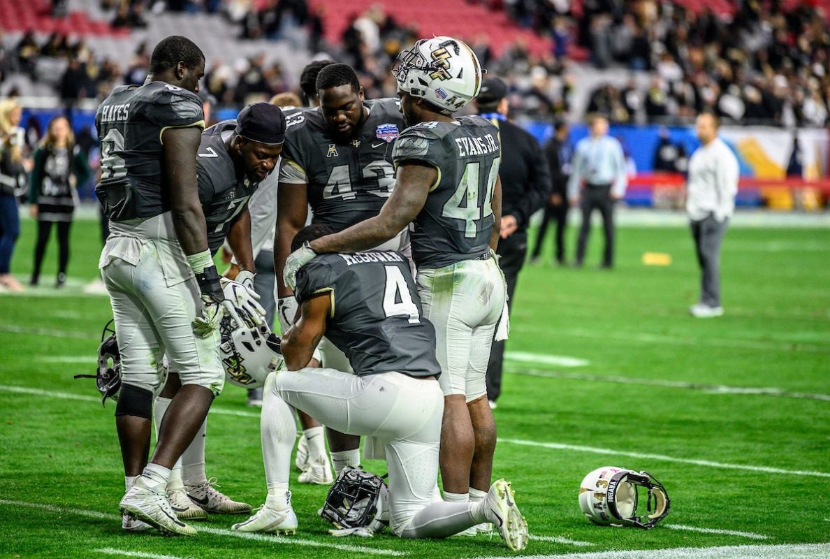 UCF football team huddles on the field