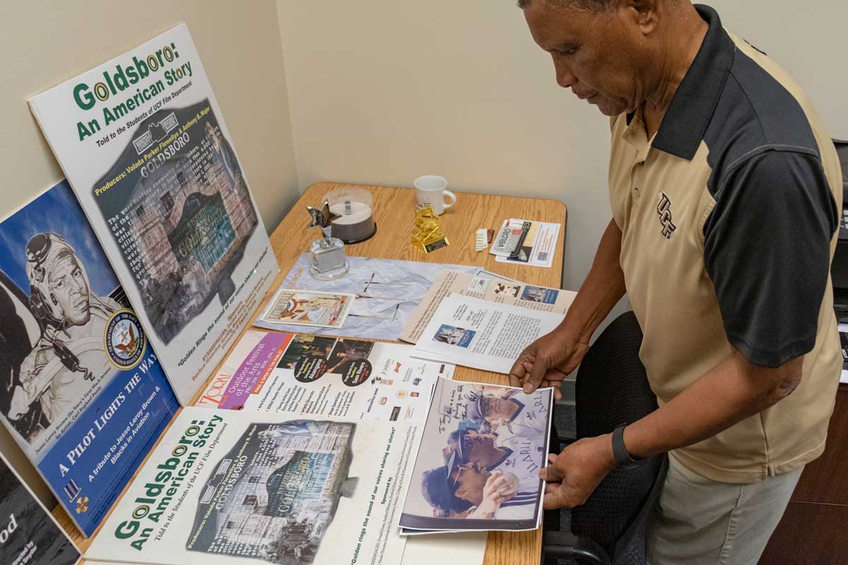 Man looks down at wood table that features various news publications on display