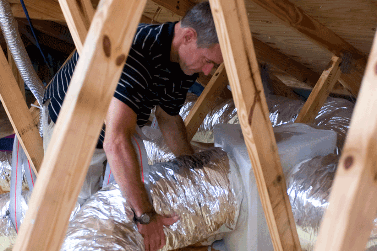 Man connects HVAC system in attic