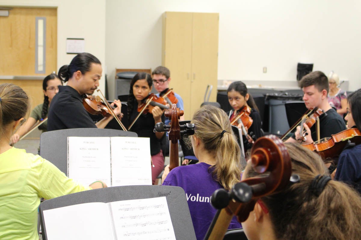 Professor leading violin students in a practice.