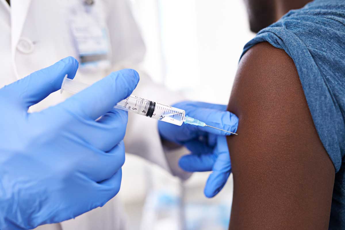 Closeup of a doctor wearing blue gloves administers a shot to an arm