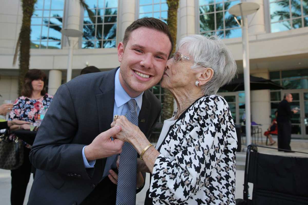 Elderly woman kisses cheek of man in suit