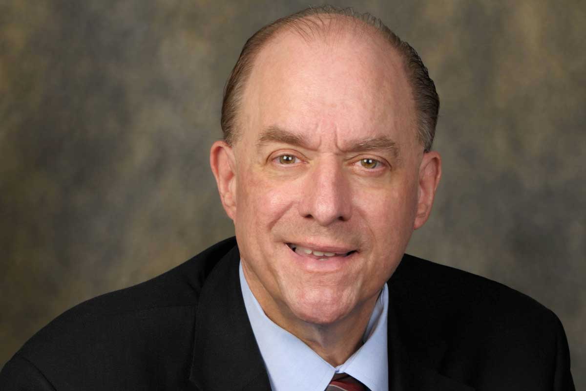 Headshot of man wearing black suit