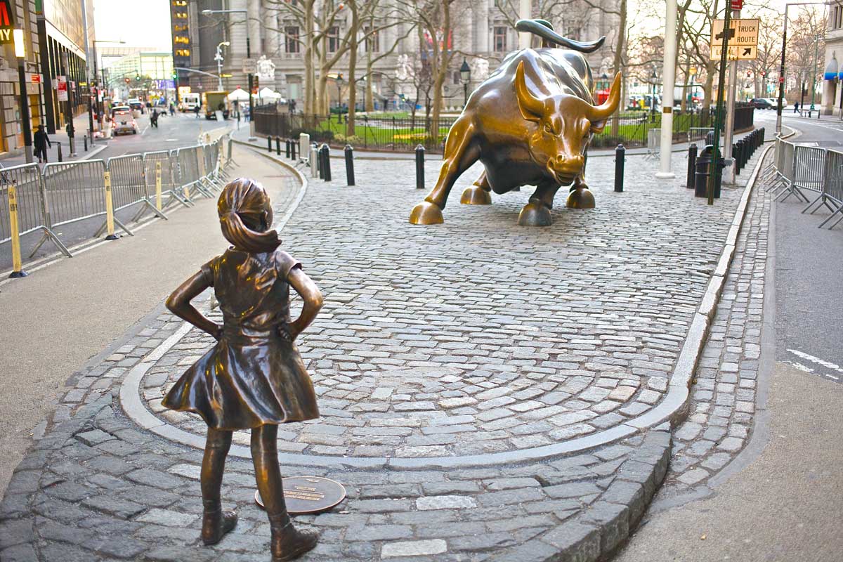 statue of girl facing off against Wall Street Bull in New York City