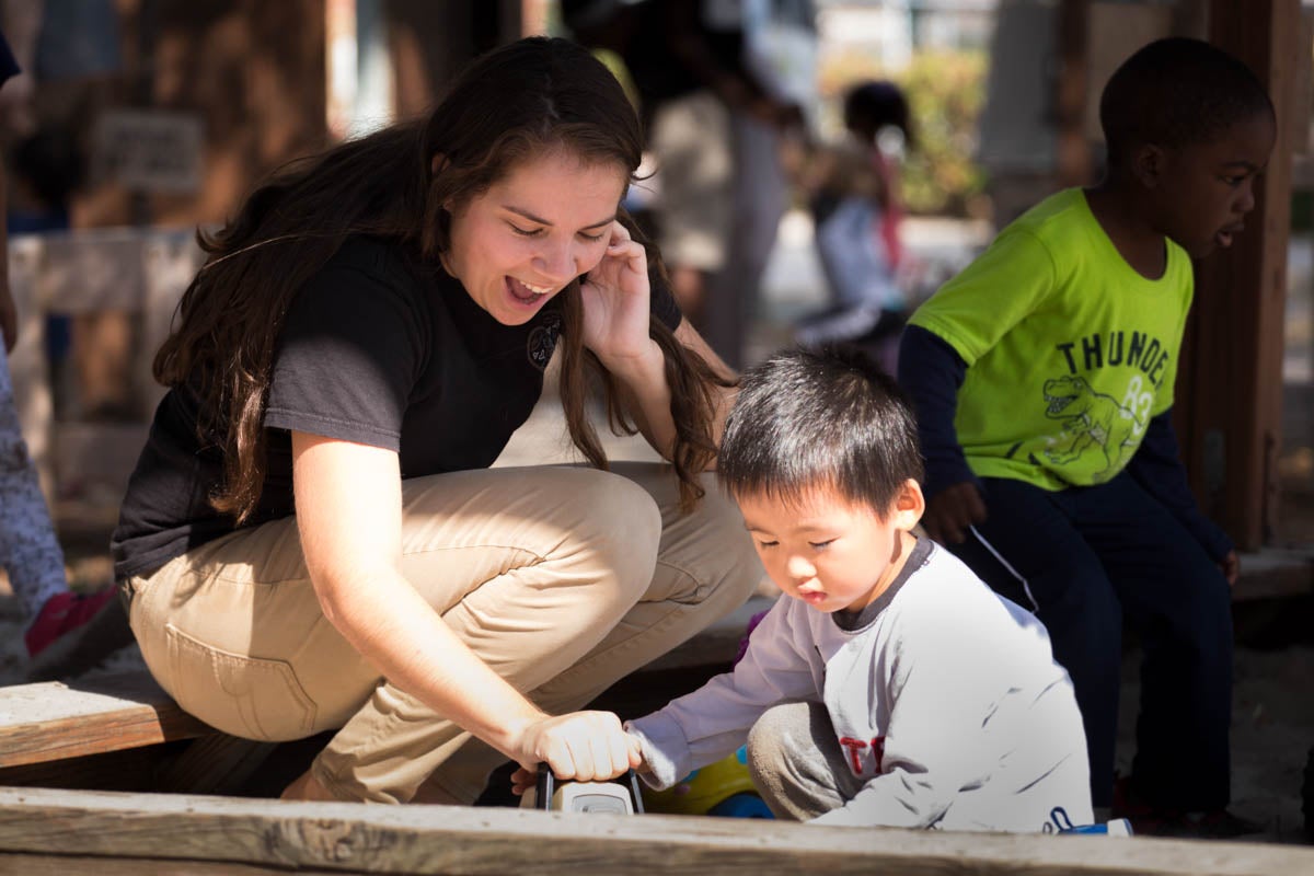 Student working with a young boy on an outside project