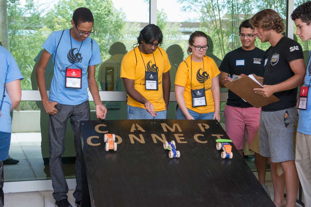 Three students release boxcar races down a black ramp