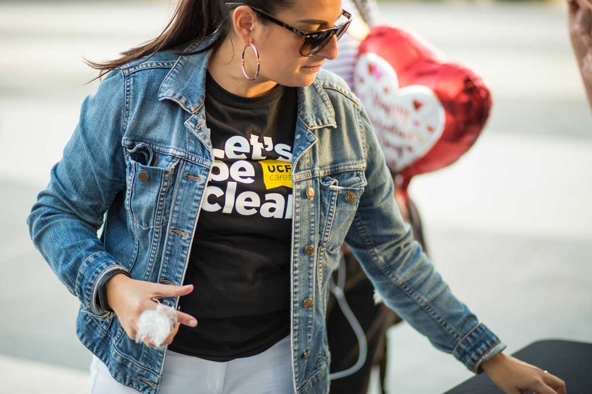 Woman wearing denim jacket and Let's Be Clear black t shirt looks down