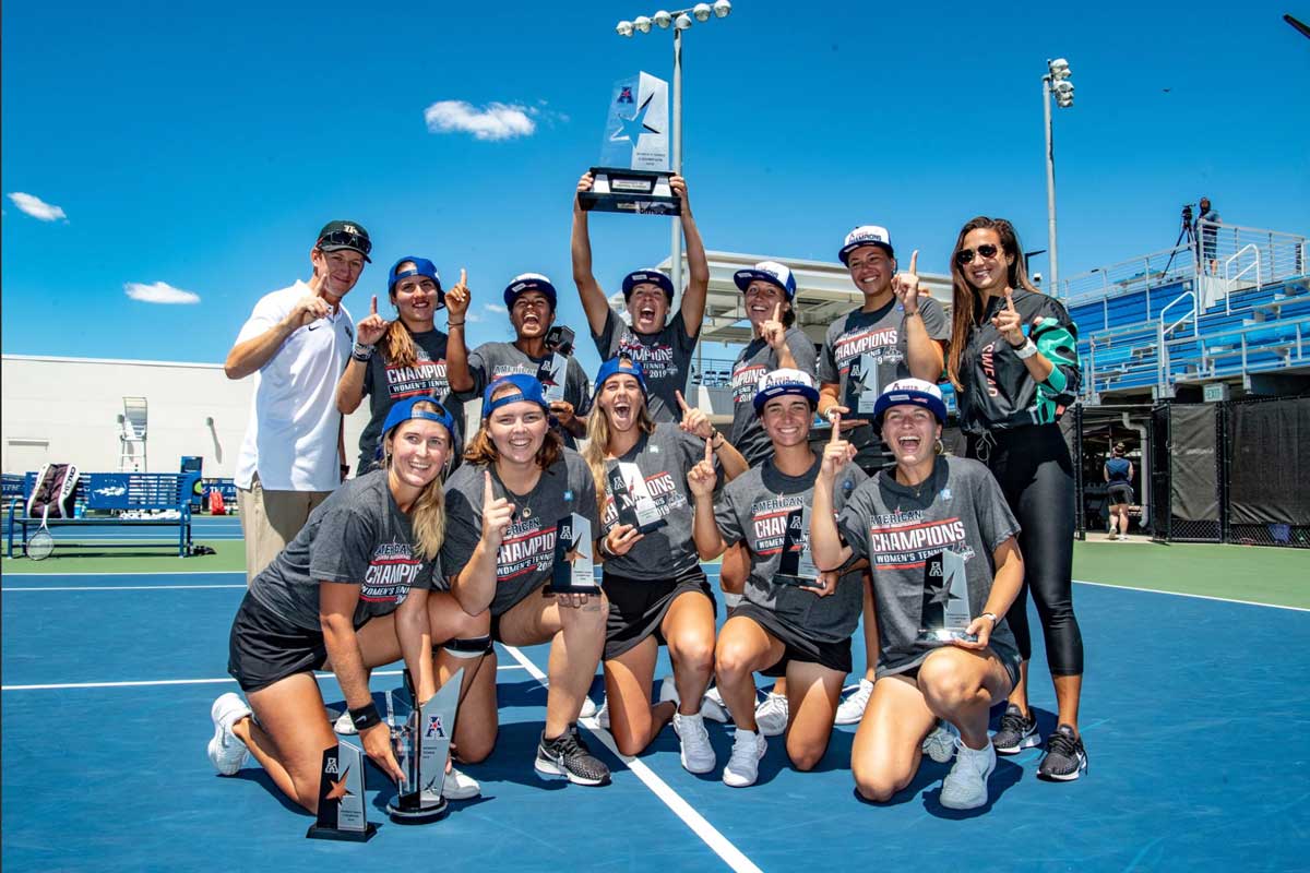 Team holds trophy on tennis court on sunny day