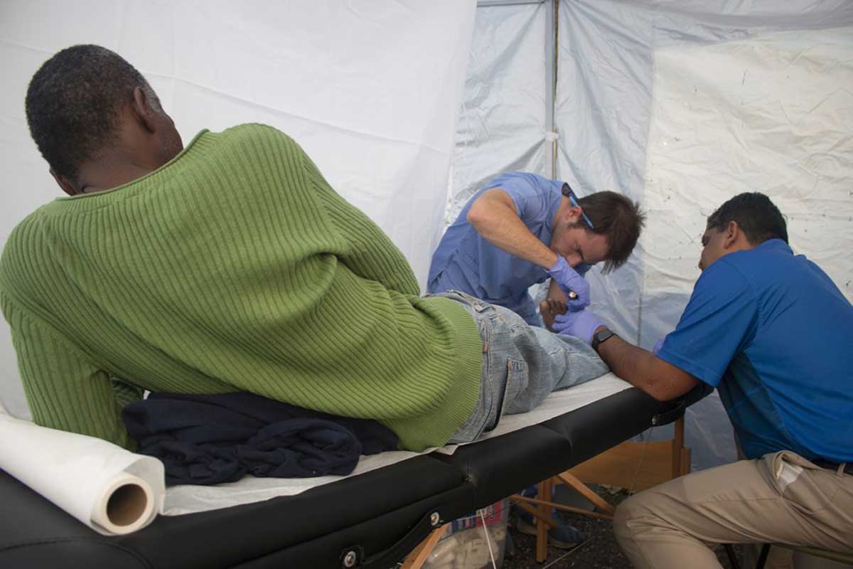 Doctors treat man's foot on a table in a white tent