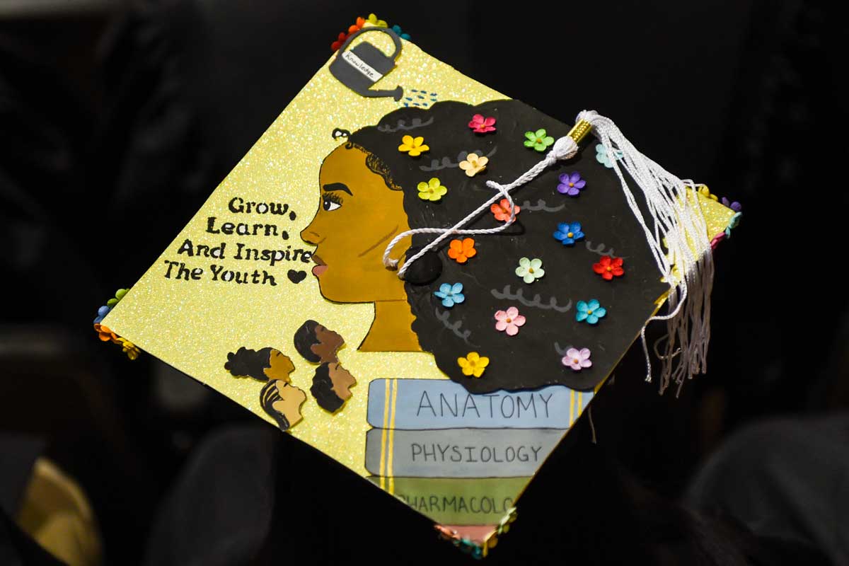 Grad cap decorated with African-American woman's face and flowers in her hair and text: Grow, Learn and Inspire The Youth