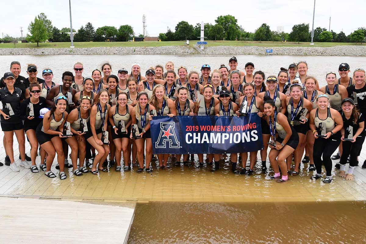 rowing team poses with American Athletic Conference championship banner