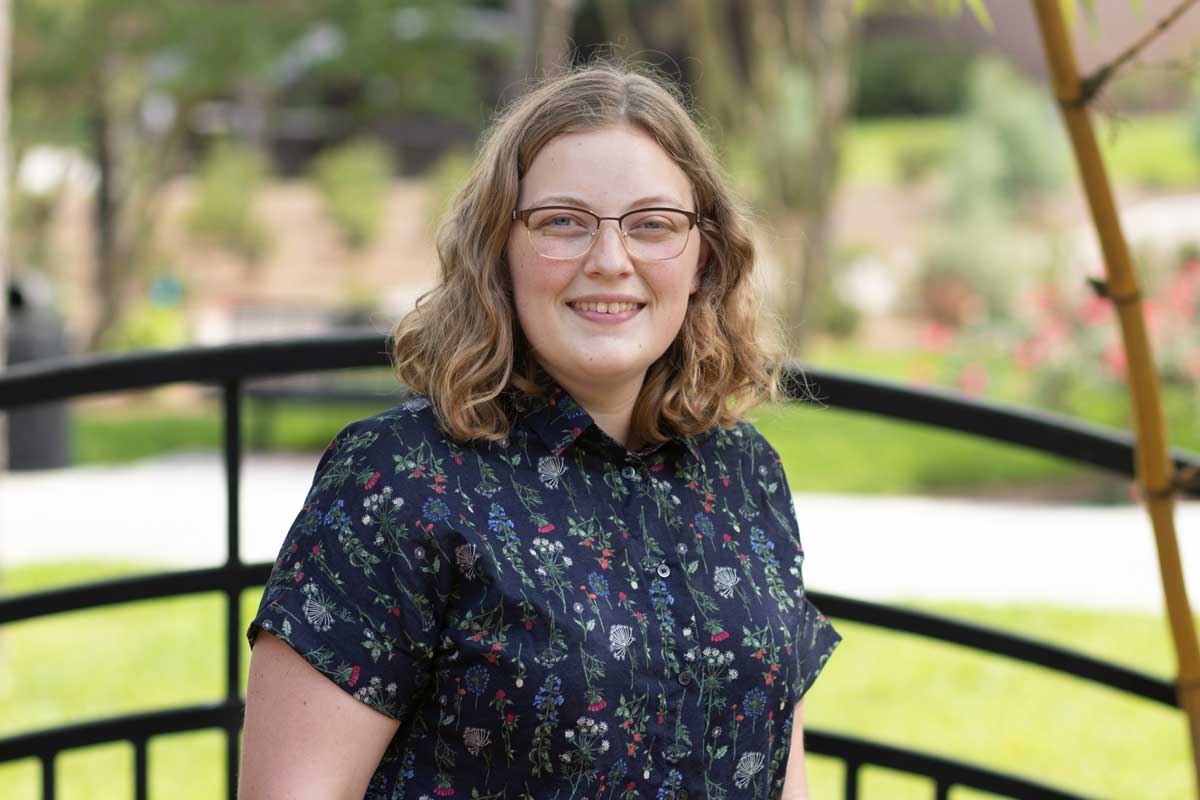 woman wearing glasses sits outside