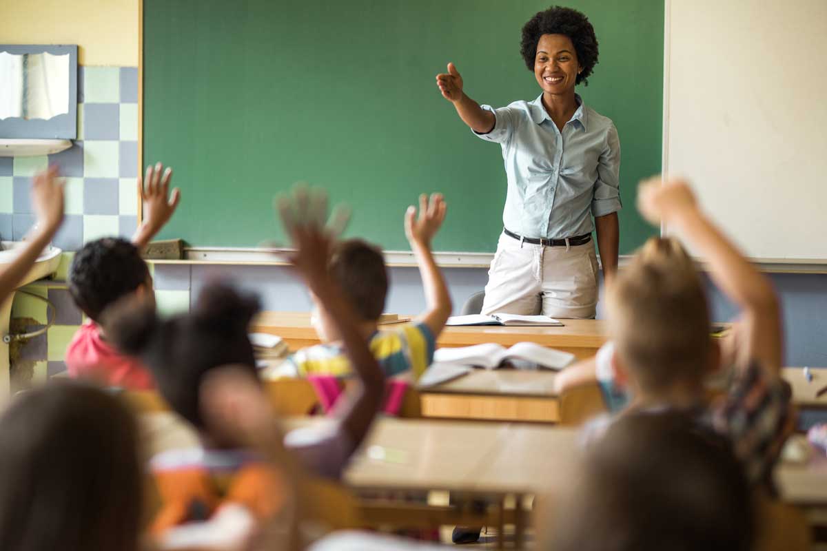 Teacher stands in front of classroom.