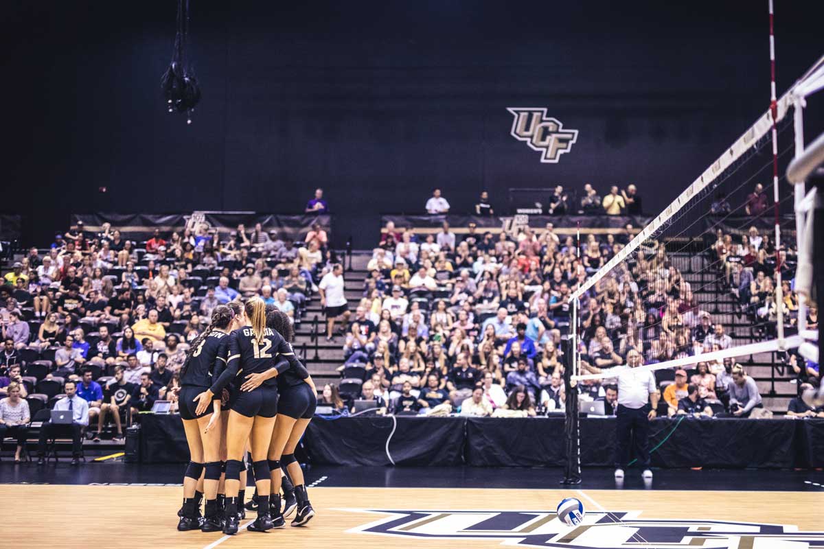 volleyball team huddles on court in front of crowd