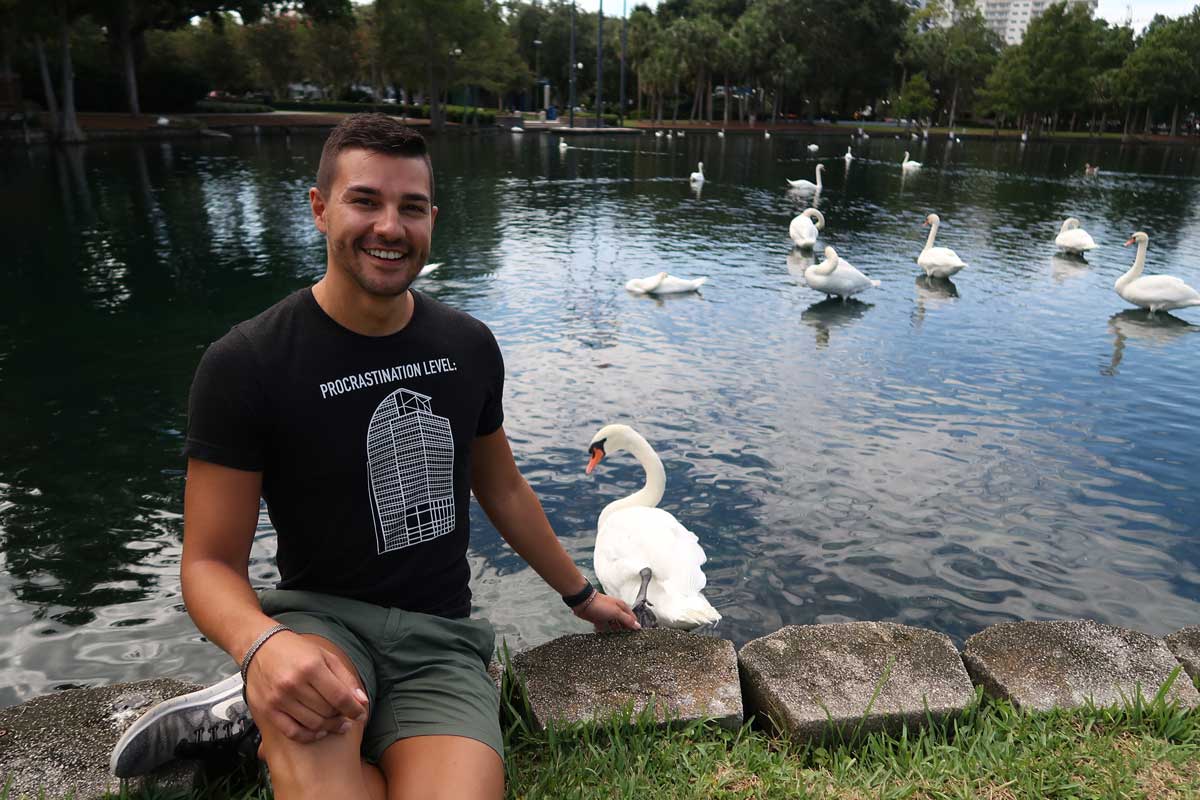 Man wearing black T shirt with design of I-4 Eyesore sits at edge of Lake Eola