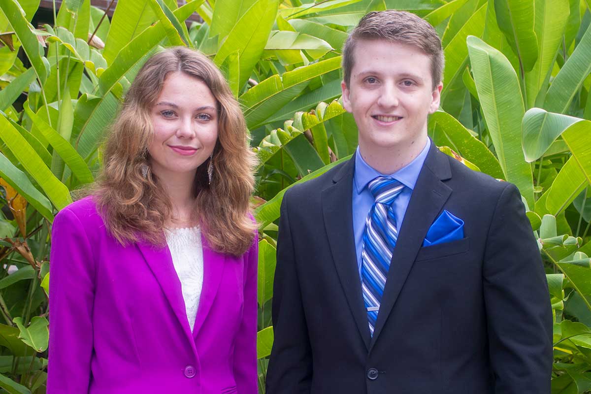 Blonde woman wearing pink blazer and male wearing business suit