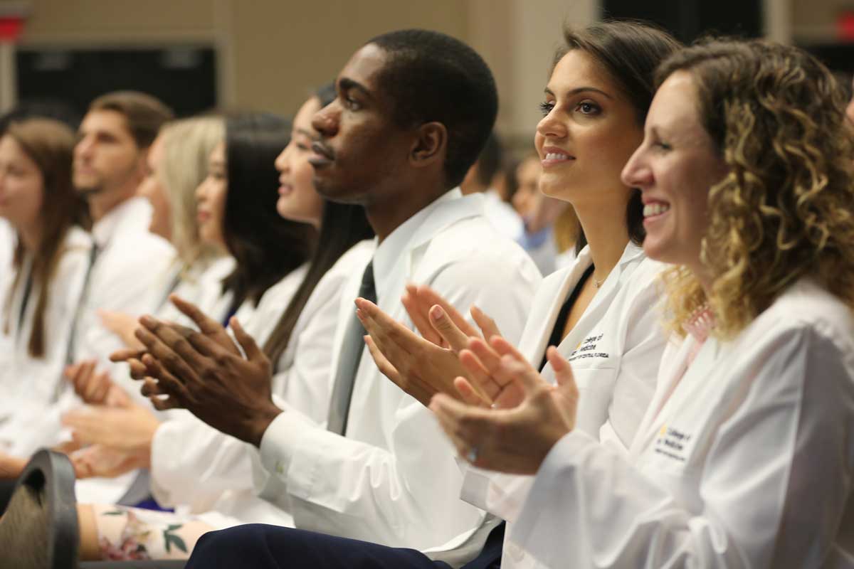 A row of medical students sit and clap