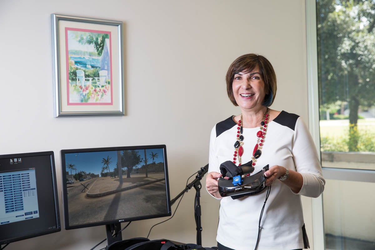 A woman holds a virtual-reality headset while smiling.