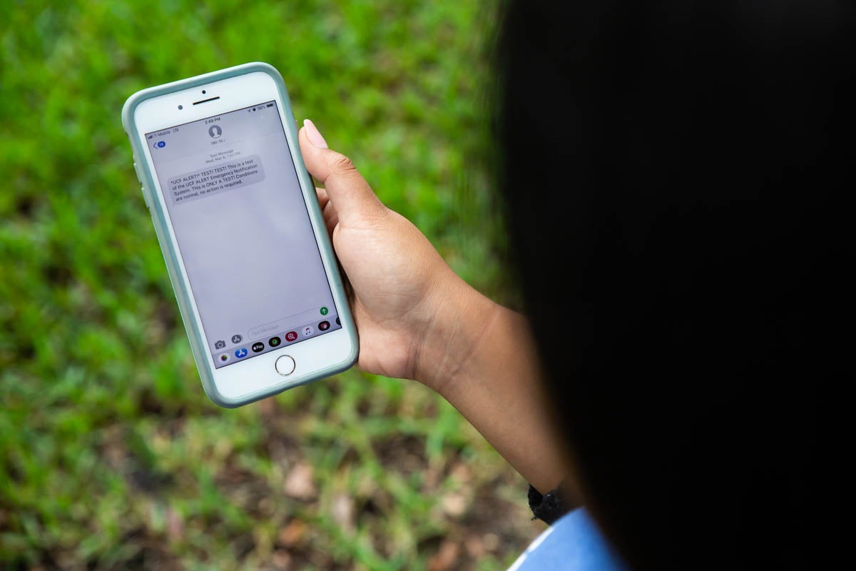 Student displaying phone screen showing alert test.