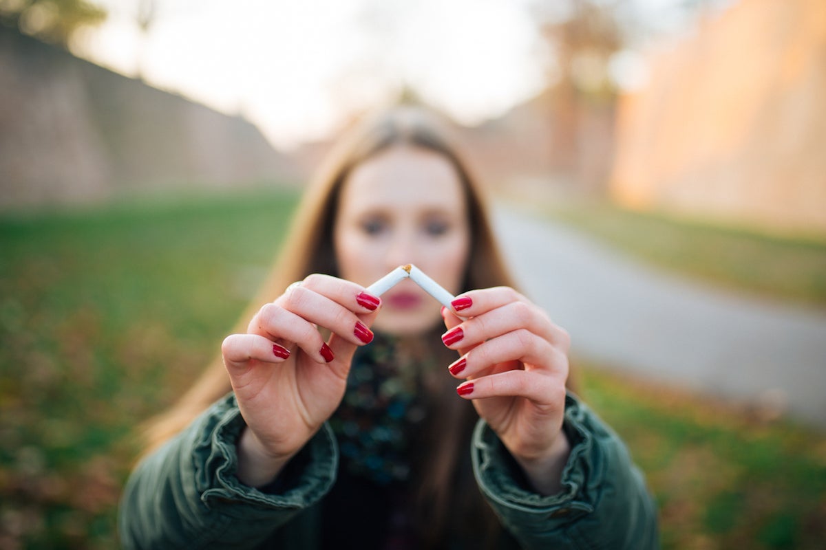 A woman breaking a cigarette.