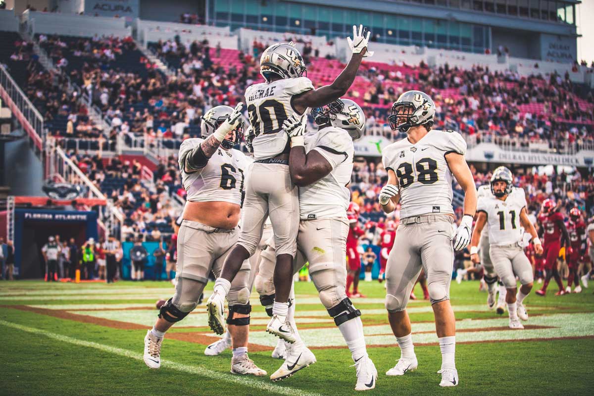 UCF football player Greg McCrae lifted into the air in celebration by his teammates in the end zone