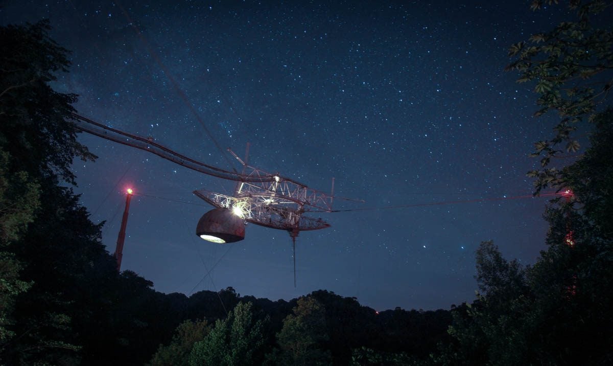 The Arecibo Observatory hangs in a star-lit sky