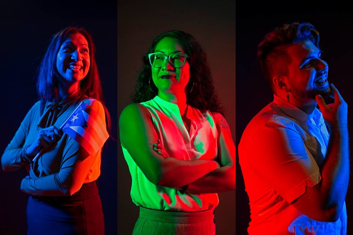 Three people pose with pride under colored lights.