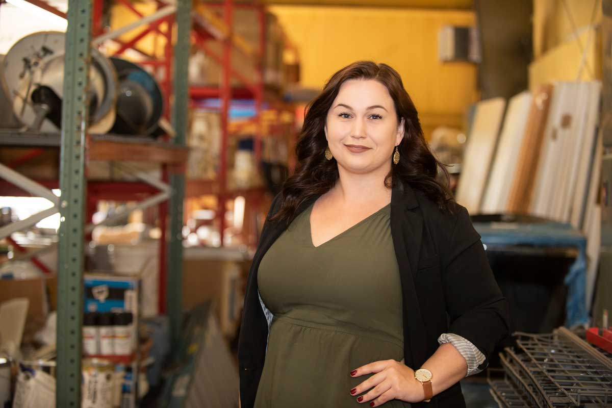 Brunette woman poses near storage shelves