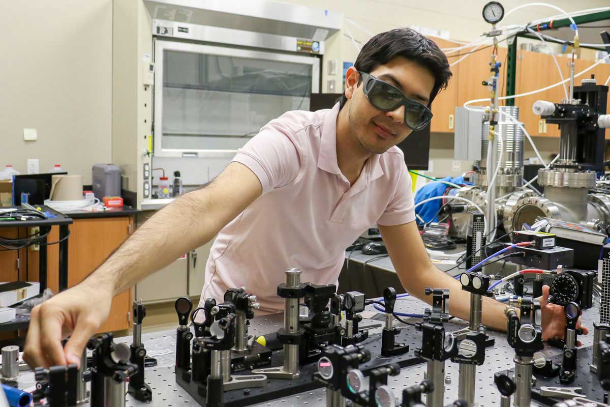 Man wearing safety goggles in lab with technical equipment on table