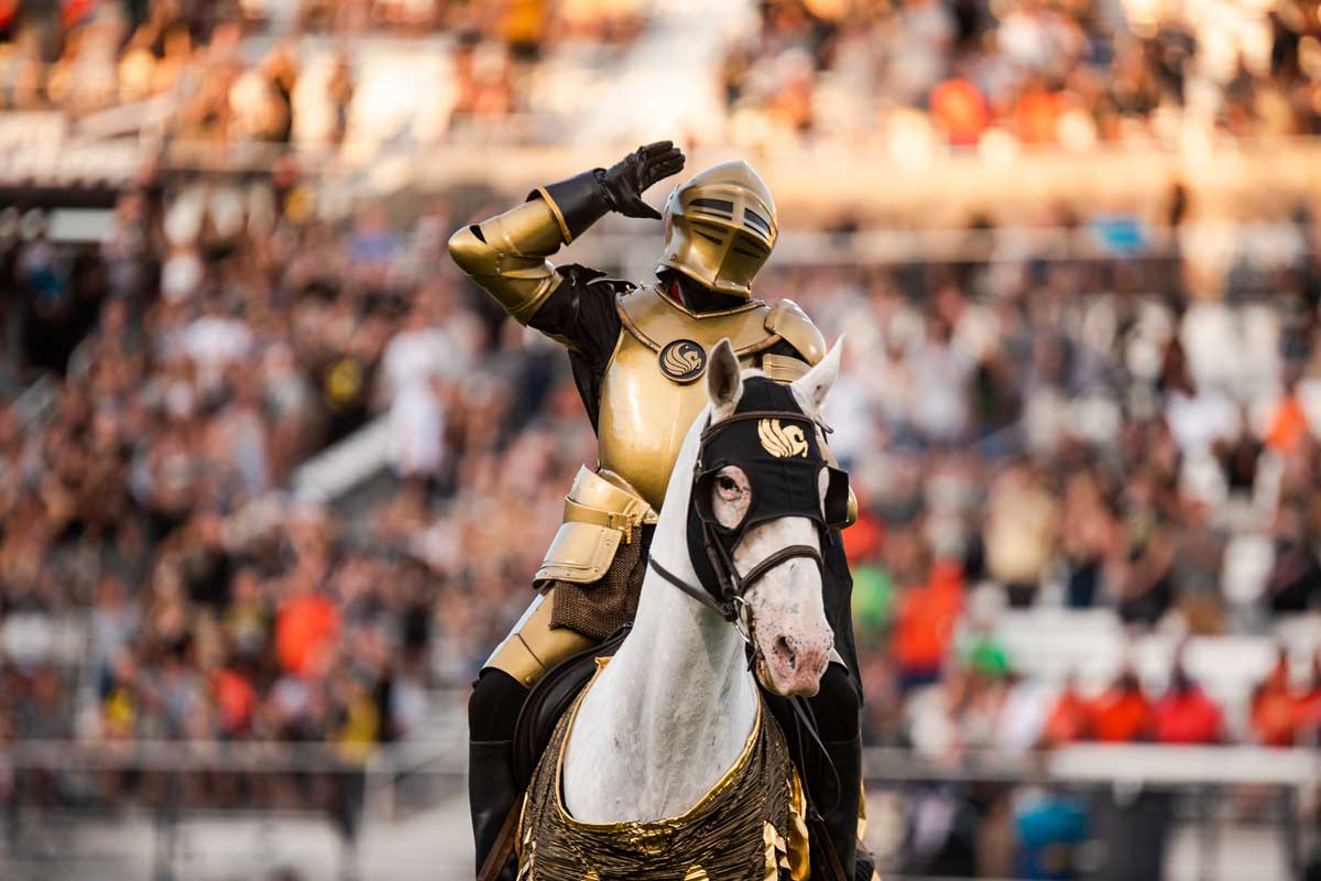 Gold Knight rides atop white horse at football stadium