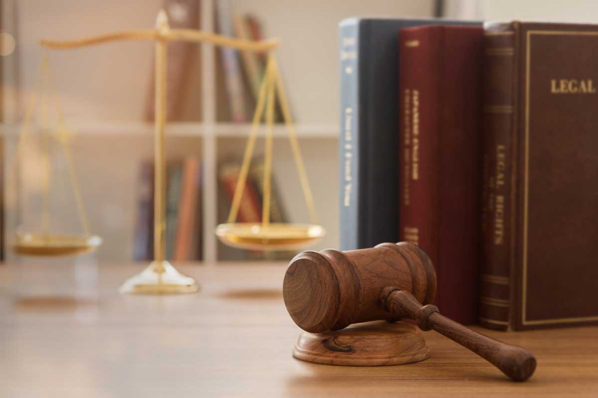 wooden gavel placed on a desk near legal books and a gold scale in the background