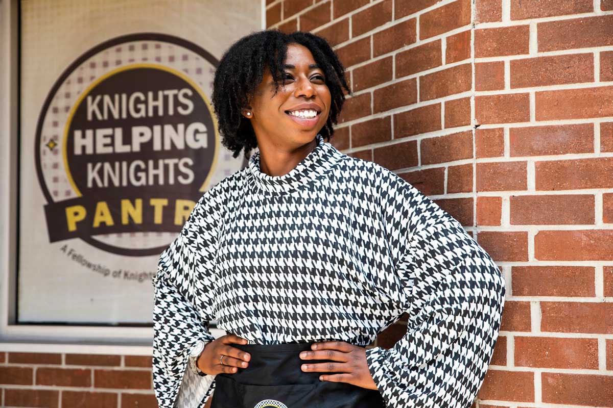Naseeka Dixon stands in front of Knights Pantry brick wall