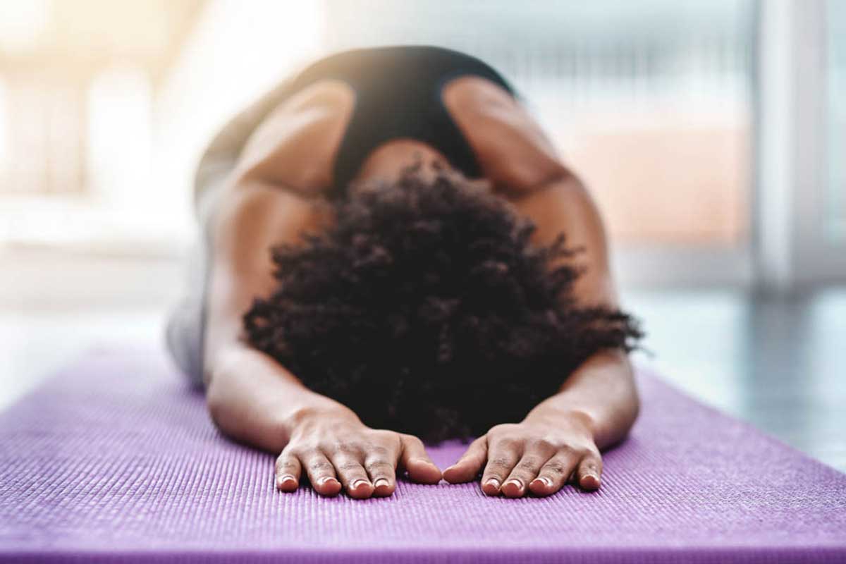 woman in child's pose on yoga mat