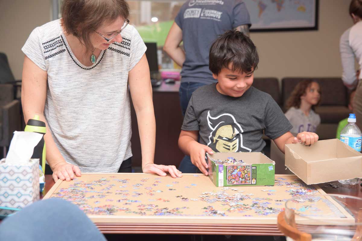 Young boy stands at table with unfinished puzzle