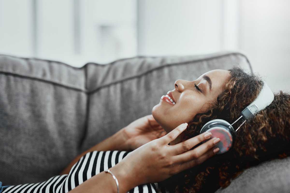 woman relaxes on couch with headphones