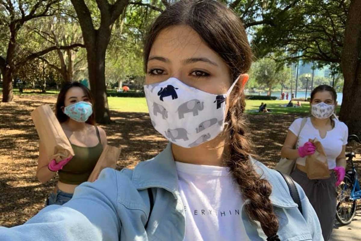 Three women wearing face masks stand outside
