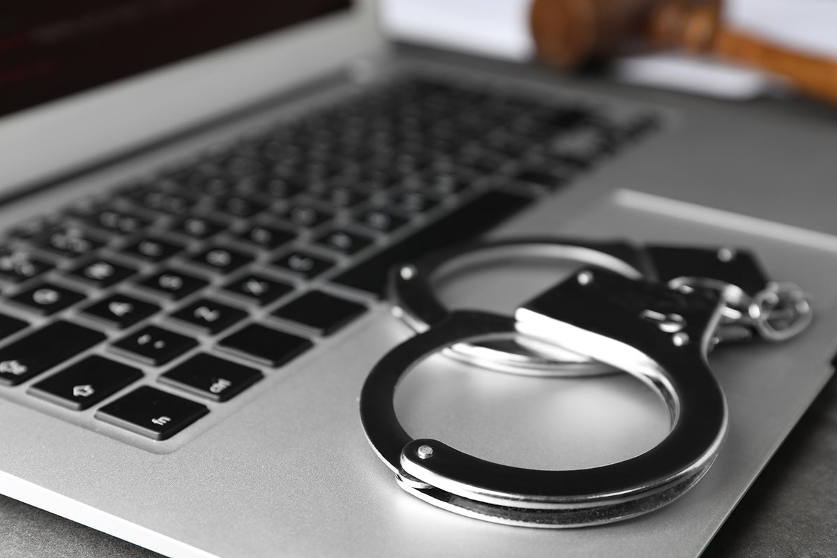 A picture of handcuffs on top of a laptop's keyboard